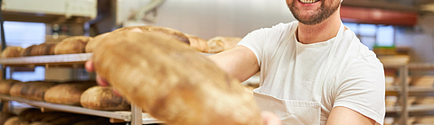Junger Bäcker zeigt ein frisches und gesundes Biobrot | © Robert Kneschke - stock.adobe.com Junger Bäcker zeigt ein frisches und gesundes Biobrot