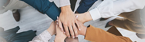 Viele Menschen strecken ihre Arme aus und legen in der Mitte ihre Hände übereinander als Zeichen der Verbundenheit. | © Azee Jacobs/peopleimages.com - Stock.Adobe.com Viele Menschen strecken ihre Arme aus und legen in der Mitte ihre Hände übereinander als Zeichen der Verbundenheit.